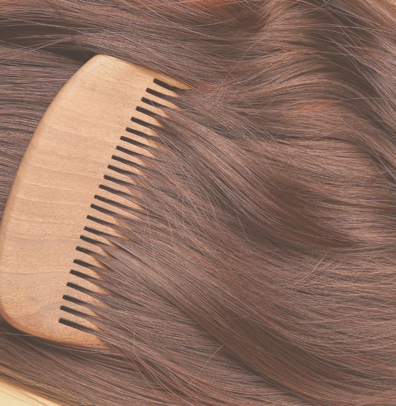 hairstylist Lauren sits on green couch under shelf of hair products