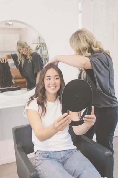 New Guests 2 client looking at new hairstyle in a mirror while hair stylists looks on