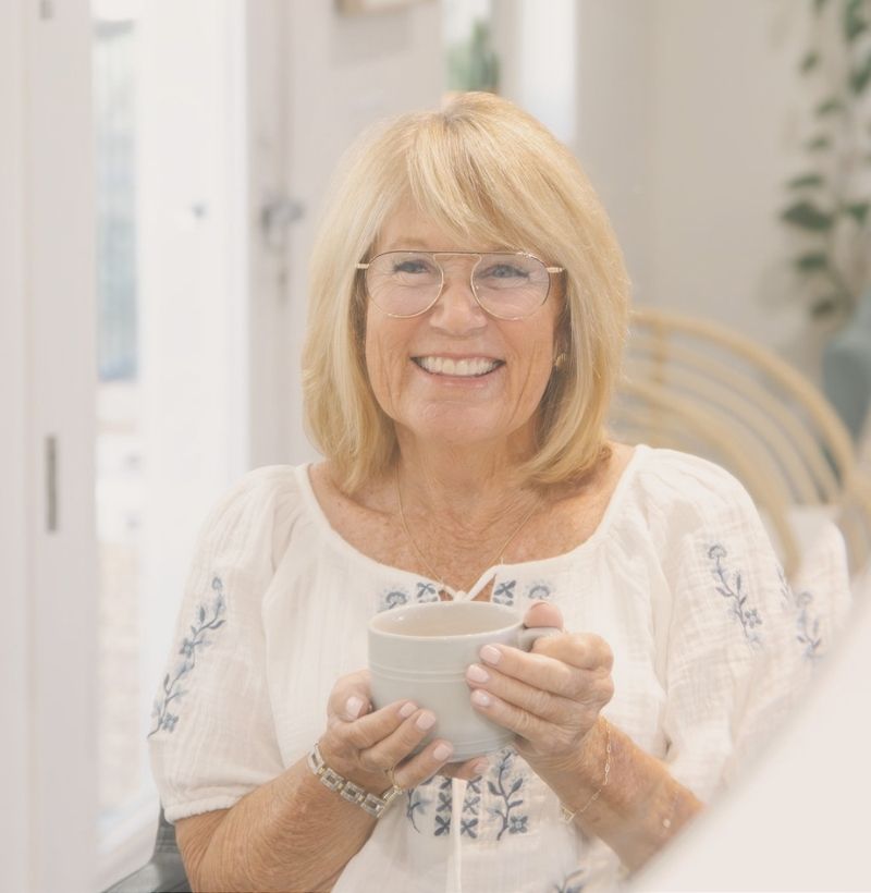 woman with freshly styled shoulder length blonde hair holding a cup of coffee